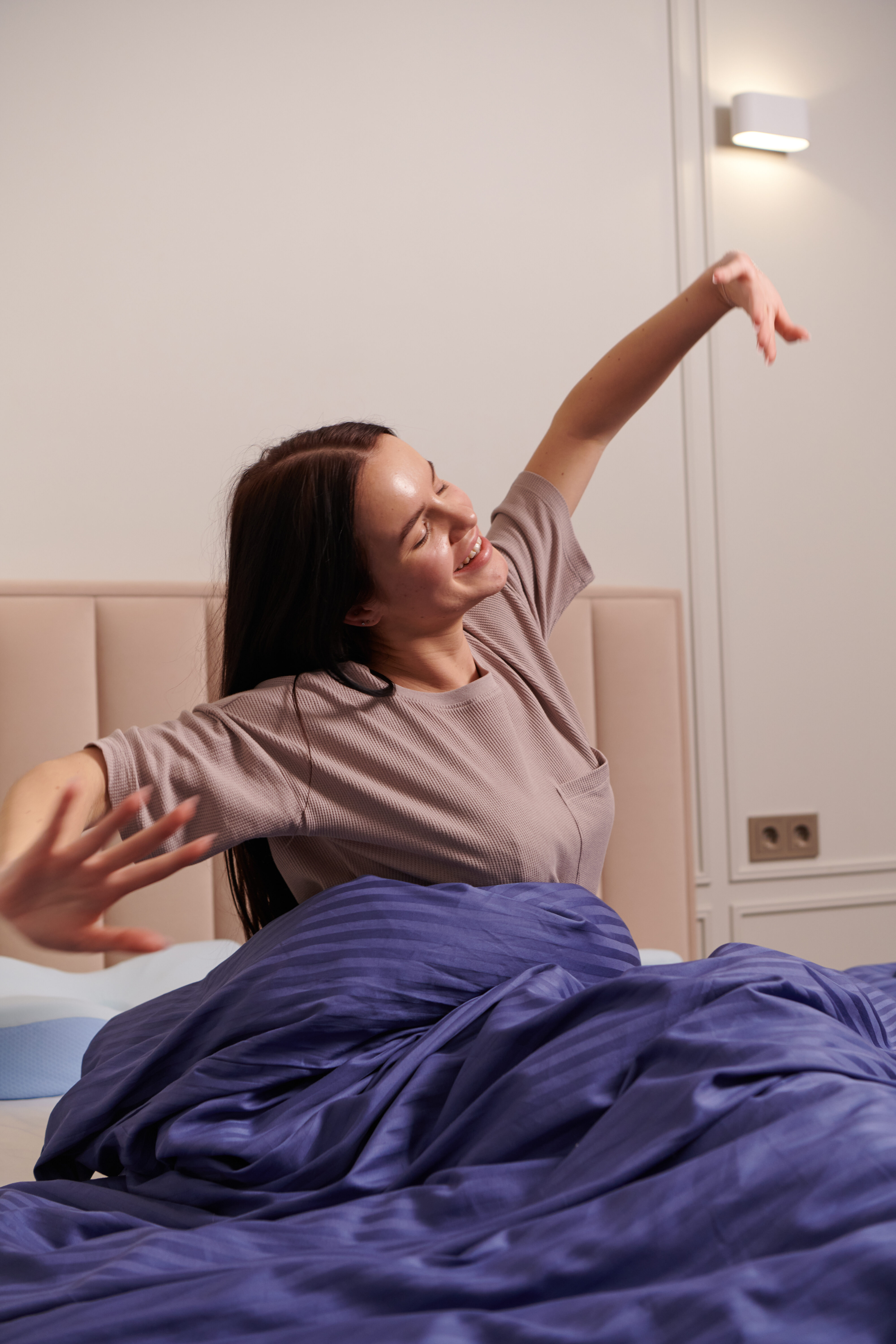 Woman waking up and raising her arms in relief after sleeping with the Derila Ergo