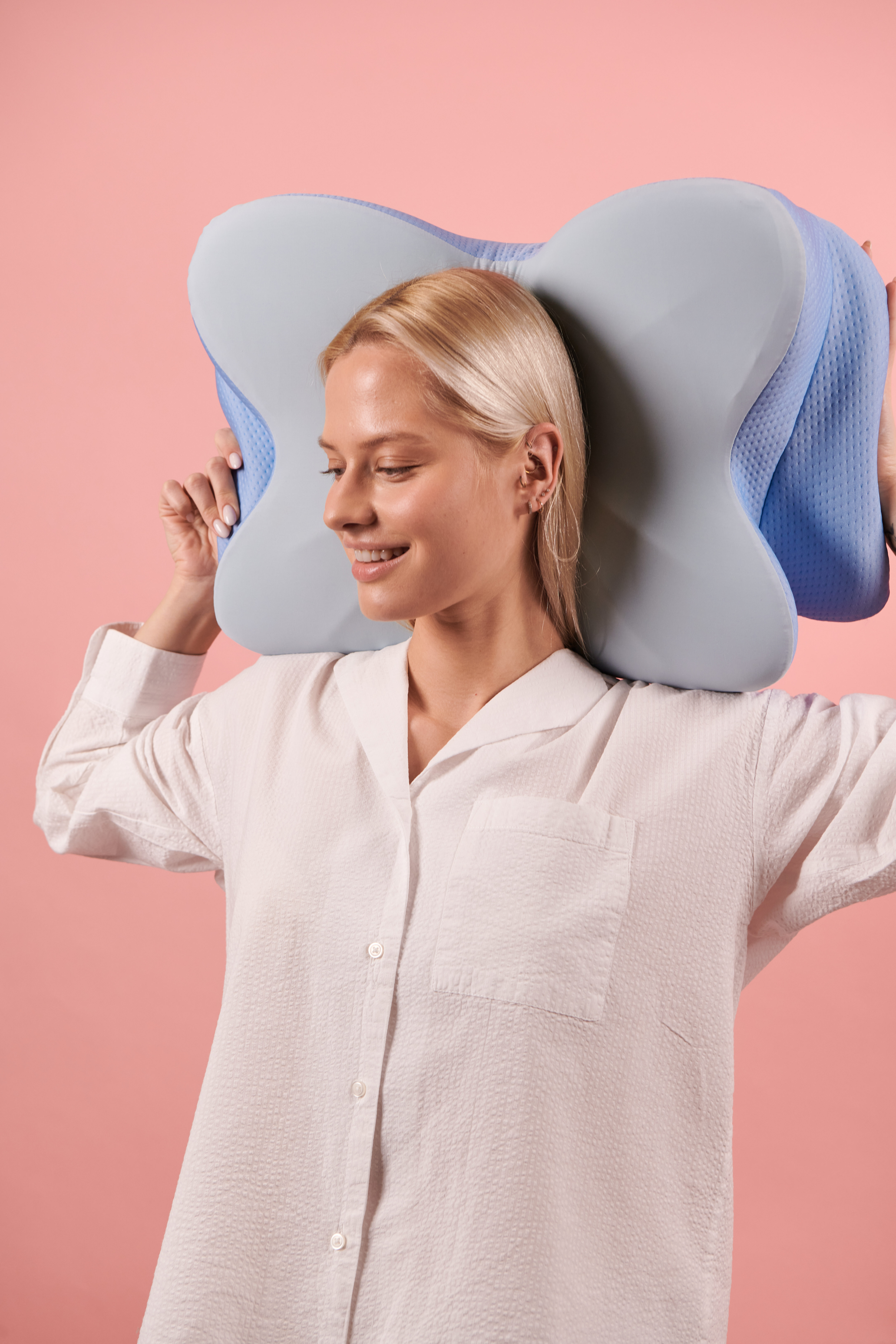 Woman holding the Derila Ergo pillow against her neck with a satisfied, relaxed expression